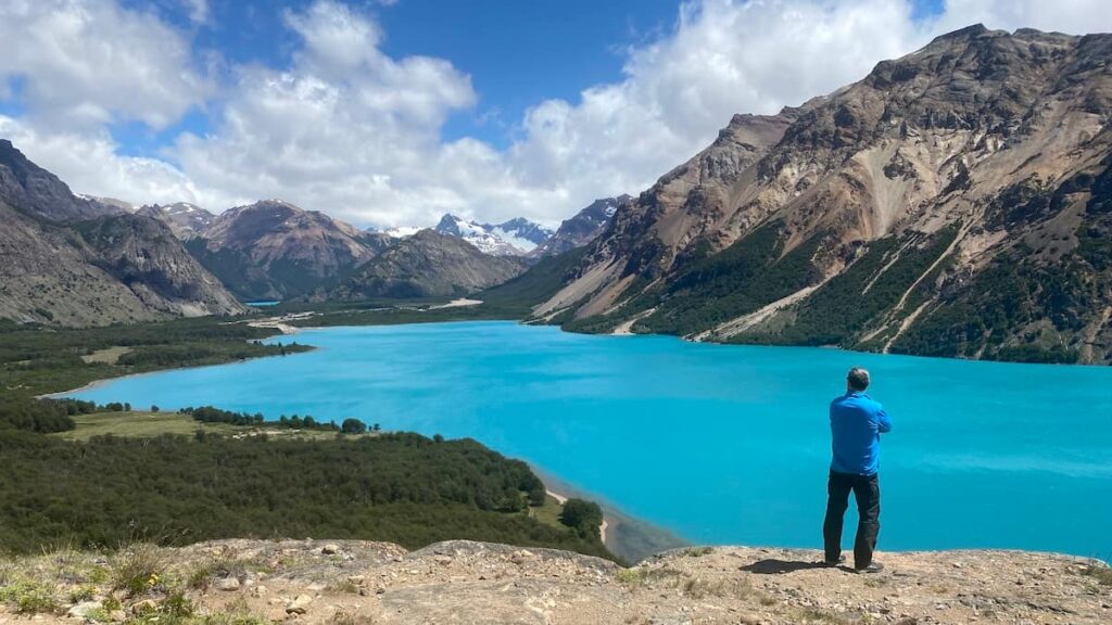 Mann von hinten an einem Gebirgssee stehend mit einer Berglandschaft im Hintergrund